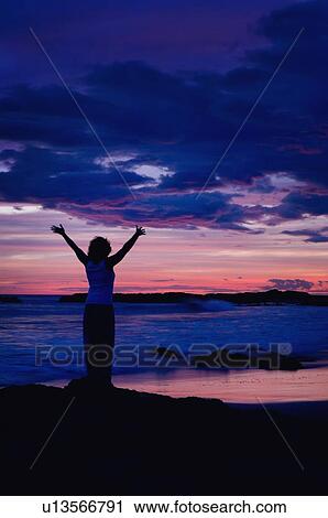 Stock Image - Woman on a beach at sunset . Fotosearch