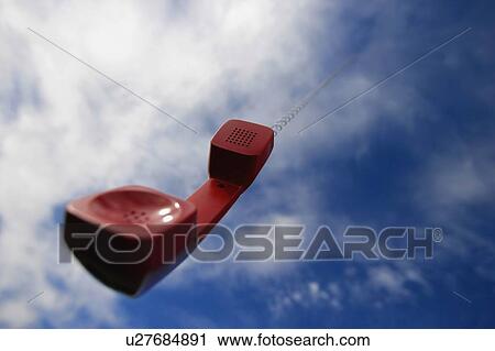 Stock Image - A telephone receiver dangling from the sky. Fotosearch