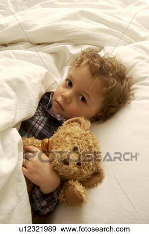 Boy laying in bed with teddy bear View Large Photo Image Stock Photo - Boy laying in bed with teddy bear. Fotosearch