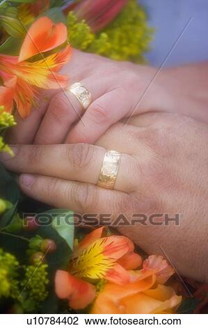 Stock Image - Closeup of rings on bride and grooms fingers . Fotosearch