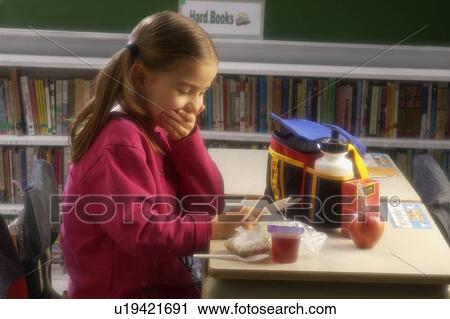 Girl eating lunch at desk reading a card View Large Photo Image Stock Image - Girl eating lunch at desk reading a card. Fotosearch