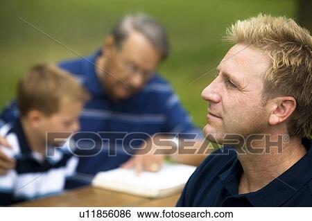 Stock Photograph - Man reflecting while his family is reading. Fotosearch