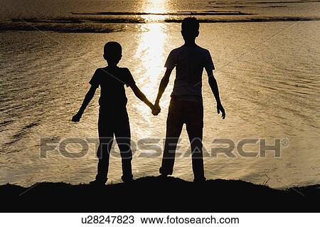 Two boys at the water's edge View Large Photo Image Stock Image - Two boys at the water's edge. Fotosearch
