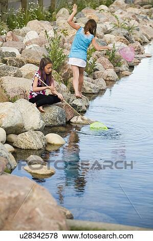Stock Photo - Two girls playing by the water. Fotosearch
