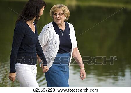 Two women walking beside a lake View Large Photo Image Stock Photo - Two women walking beside a lake. Fotosearch