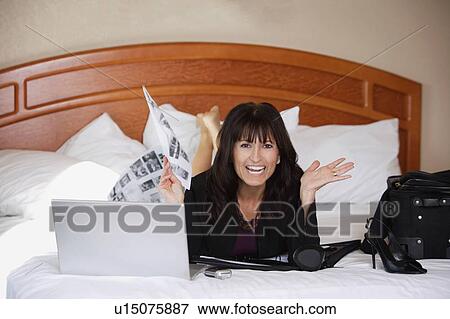 Stock Photo - Woman working on bed. Fotosearch