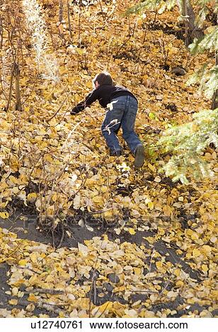 Stock Image - Boy climbing a steep hill in fall. Fotosearch