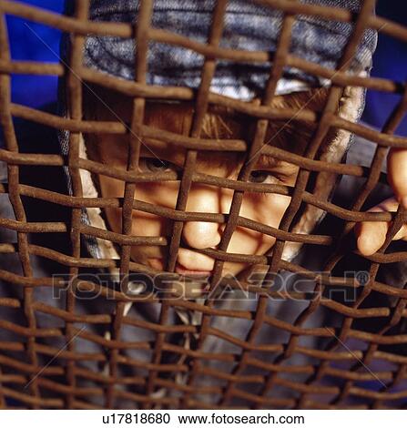 Stock Image - Child looking through rusty gate. Fotosearch