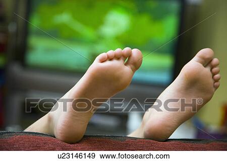 Stock Photo - Child lying on sofa with feet in air . Fotosearch