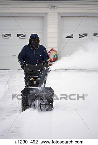 Stock Image - Man operating a snow blower. Fotosearch