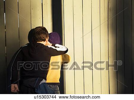 Two boys peeking through the fence View Large Photo Image Picture - Two boys peeking through the fence. Fotosearch