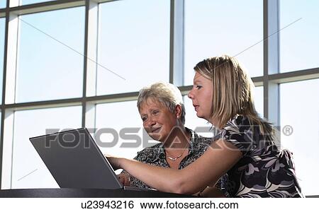 Two women looking at personal computer View Large Photo Image Stock Photograph - Two women looking at personal computer. Fotosearch