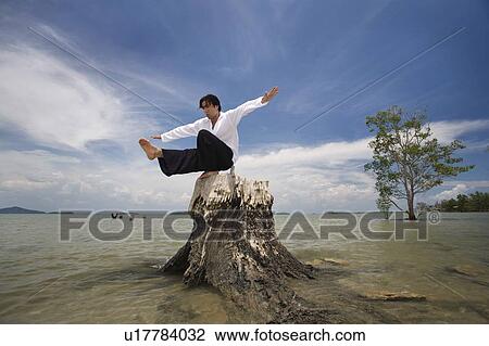A man balancing on a tree stump on a beach in Koh Lanta, Thailand View Large Photo Image Stock Image - A man balancing on a tree stump on a beach in Koh Lanta, Thailand. Fotosearch