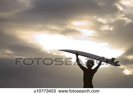 Stock Image - A surfer on Muriwai Beach, New Zealand. Fotosearch