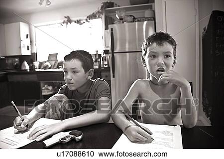 Stock Image - Boys drawing at kitchen table. Fotosearch