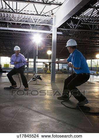Picture - Engineers playing tug of war on construction site. Fotosearch