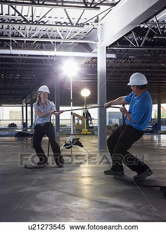Stock Photography - Engineers playing tug of war on construction site. Fotosearch