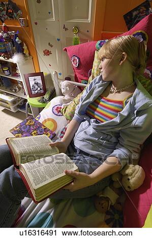 Stock Image - Girl reading Bible in bedroom. Fotosearch