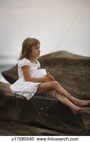 Girl sitting on a rock View Large Photo Image Stock Image - Girl sitting on a rock. Fotosearch