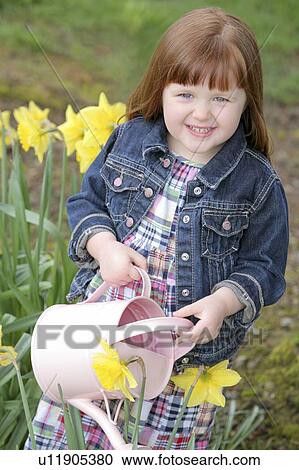 Stock Image - Little girl watering flowers. Fotosearch