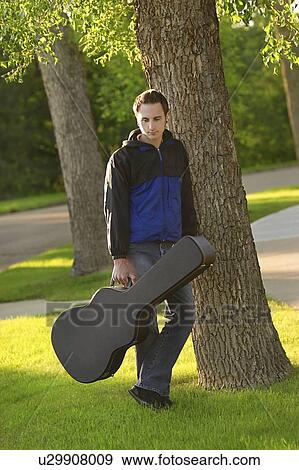 Stock Photo - Man posed with his guitar case. Fotosearch