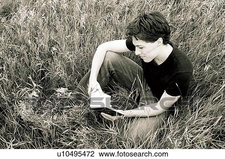 Stock Image - Man reading in the grass. Fotosearch