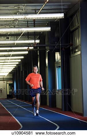 Stock Image - Man running on an indoor track. Fotosearch