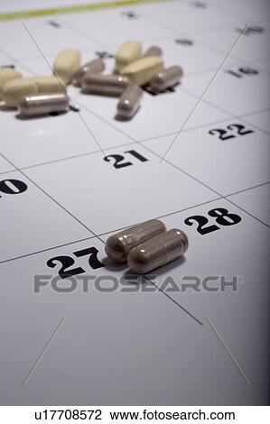 Stock Image - Pills scattered on a calendar page. Fotosearch