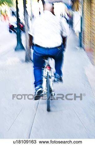 Stock Image - Rear view of man riding bike. Fotosearch