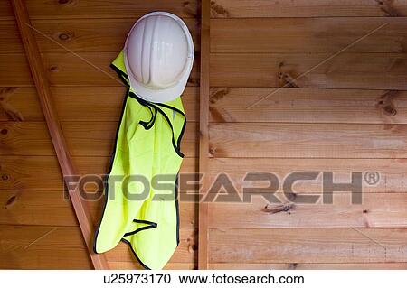 Stock Image - Reflective vest and hardhat hanging on wall. Fotosearch