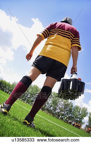 Stock Image - Rugby player on the sideline with refreshments. Fotosearch