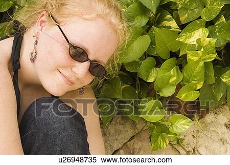 Teenage girl in sunglasses by green plant View Large Photo Image Stock Photography - Teenage girl in sunglasses by green plant. Fotosearch