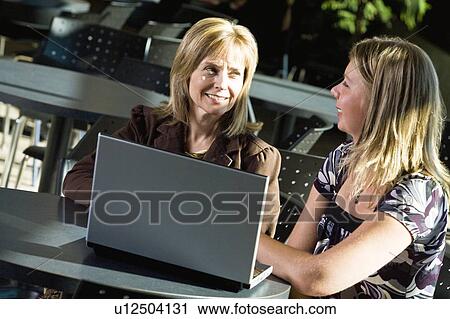 Stock Image - Two women working on a laptop. Fotosearch