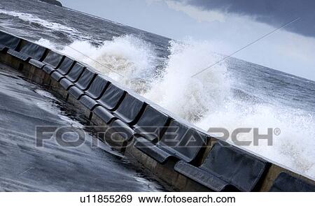 Stock Photo - Waves crashing into concrete wall. Fotosearch