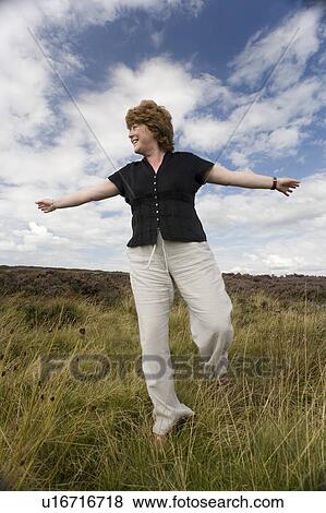 Woman balancing in a field View Large Photo Image Stock Photo - Woman balancing in a field. Fotosearch