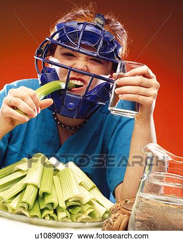 Stock Photo - Woman in sports equipment eating celery. Fotosearch