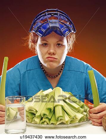 Stock Image - Woman in sports gear eating celery. Fotosearch