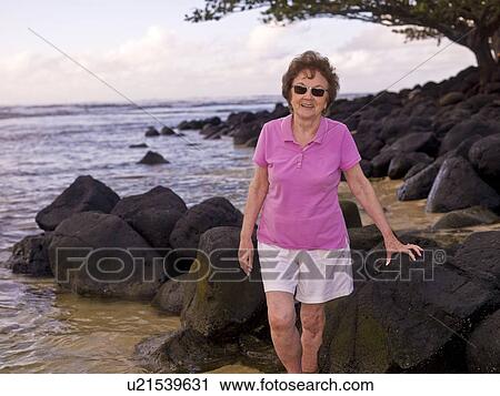 Stock Image - Woman on a rocky beach, Kauai, Hawaii, USA. Fotosearch