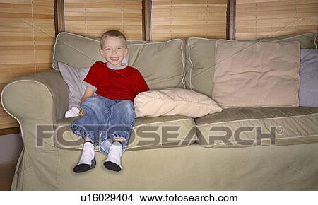 Picture - Boy sitting on couch, smiling. Fotosearch