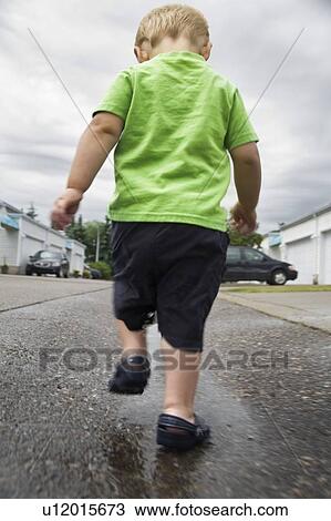 Boy walking in a puddle View Large Photo Image Stock Image - Boy walking in a puddle. Fotosearch
