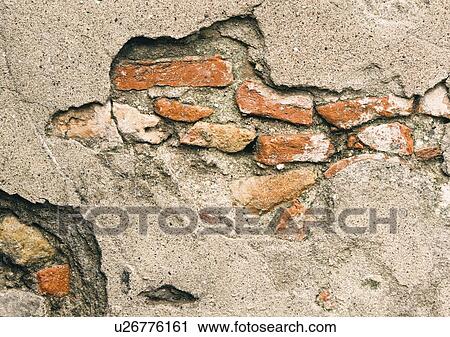 Stock Image - Broken wall revealing bricks beneath cement facing. Fotosearch