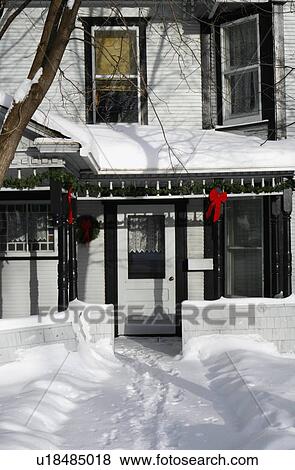 Christmas decorations hang outside on a snow covered house View Large Photo Image Stock Photo - Christmas decorations hang outside on a snow covered house. Fotosearch
