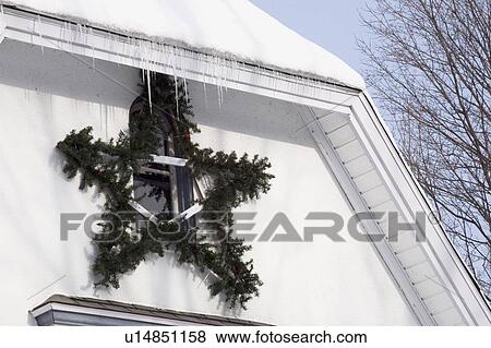 Stock Photo - Christmas decorations hanging outside a snow covered house. Fotosearch