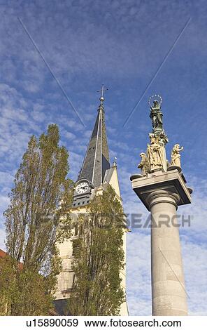 Stock Photo - Church of St. James, Ljubljana, Slovenia; St. Mary's column statue and clock tower. Fotosearch