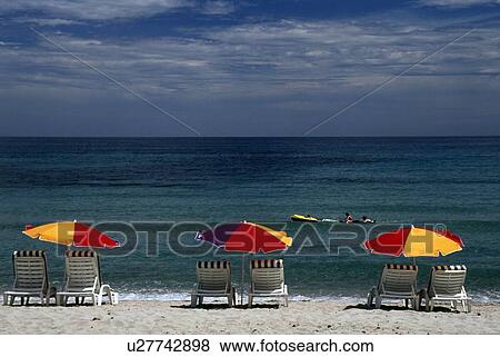 Stock Photo - Corsica, France; Lounge chairs and sun umbrellas on a Mediterranean beach. Fotosearch