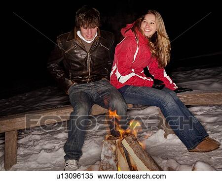 Couple sitting by a fire in the snow View Large Photo Image Stock Photography - Couple sitting by a fire in the snow. Fotosearch