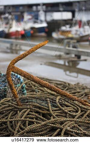 Stock Photo - East Riding, Yorkshire, England; Rusty anchor and piles of rope on the seafront. Fotosearch