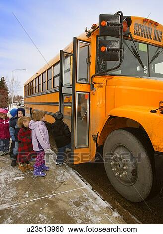 Stock Image - Elementary schoolchildren boarding school bus on a cold winter day in Edmonton Alberta Canada. Fotosearch