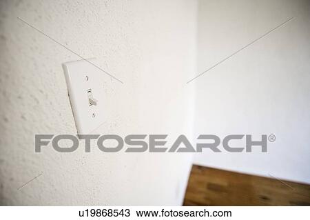 Stock Image - Empty room with white walls, white lightswitch and a wooden floor. Fotosearch