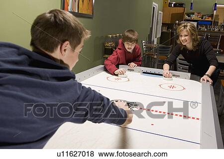 Stock Photo - Family playing air hockey. Fotosearch